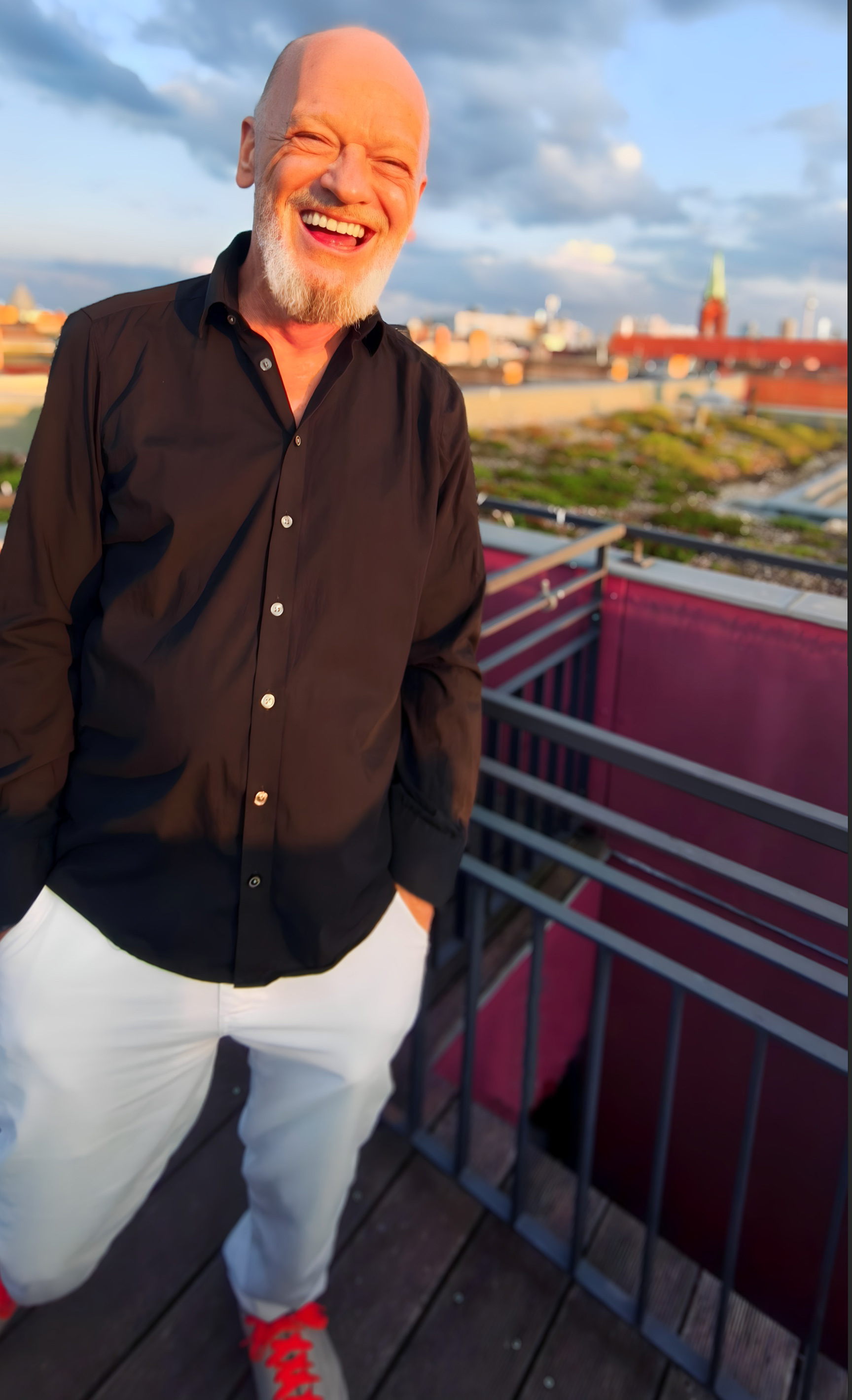 Hans Hellfried Wedenig lachend auf einer Dachterrasse in Berlin